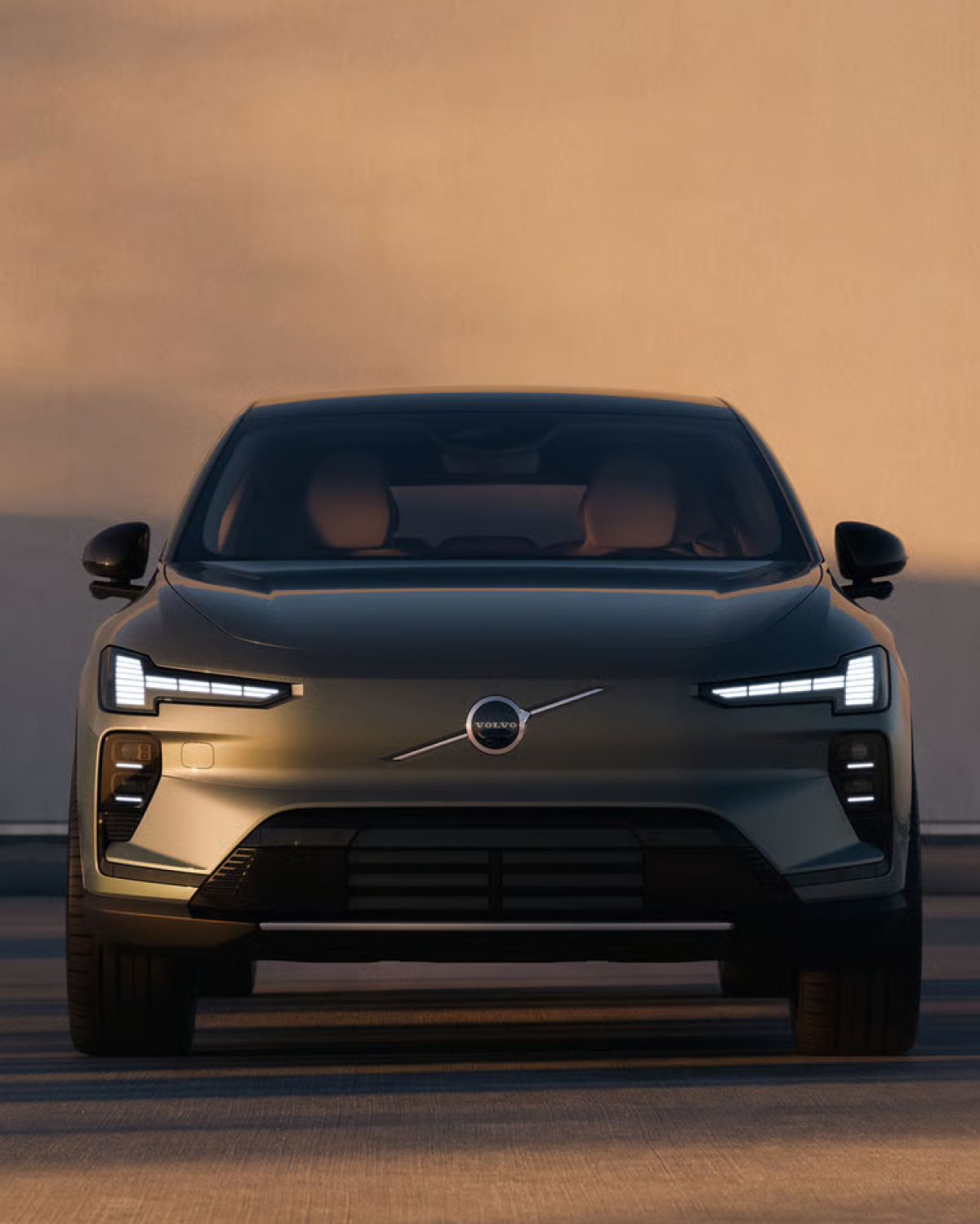 Dianteira de um SUV Volvo com os faróis acesos ao entardecer