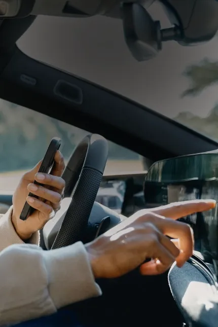 Motorista com o celular na mão tocando a tela central de um Audi