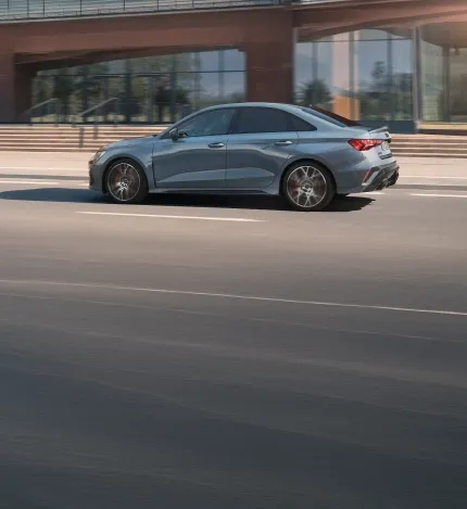 Sedã esportivo Audi cinza em movimento em uma avenida urbana, visto de perfil
