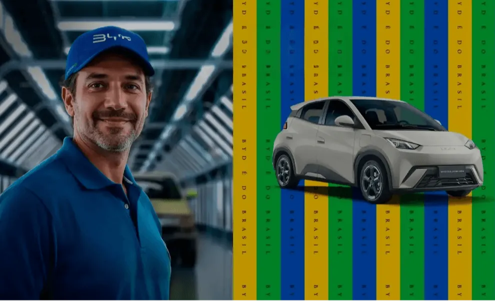 Homem de azul sorrindo e carro ao lado com faixas coloridas ao fundo.