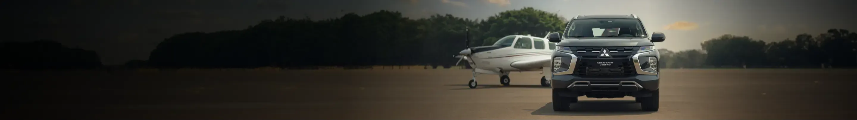 Pajero MITSUBISHI na frente de um avião em pista