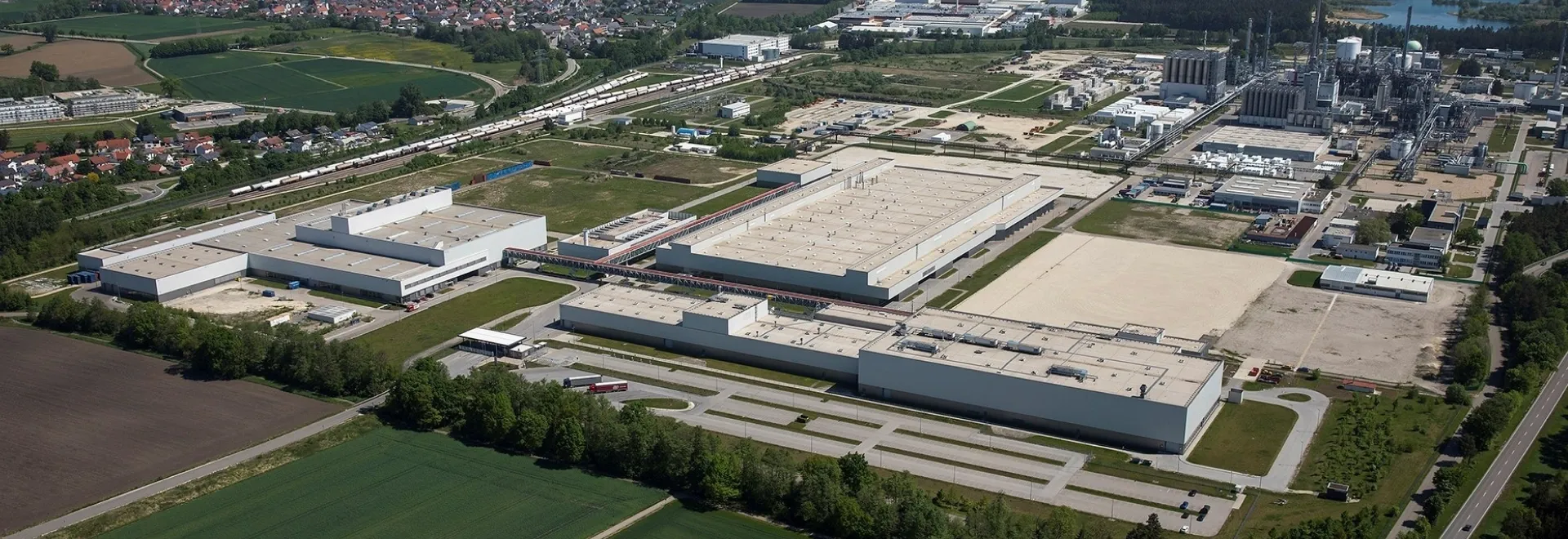 Vista aérea de um complexo industrial da Audi cercado por campos