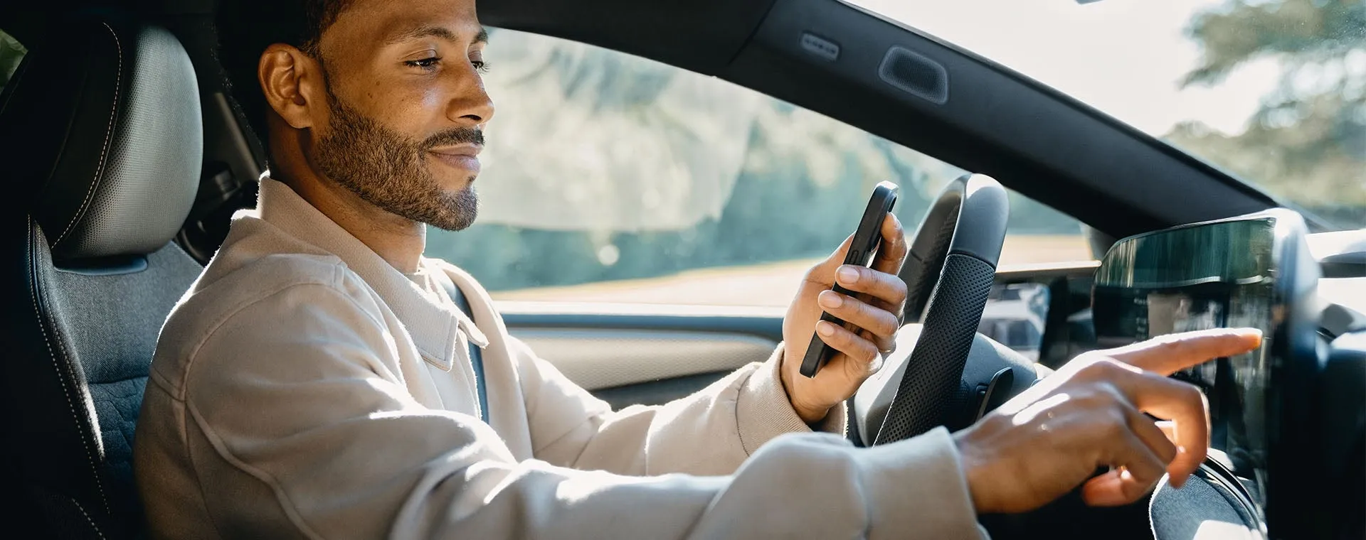 Motorista com o celular na mão tocando a tela central de um Audi