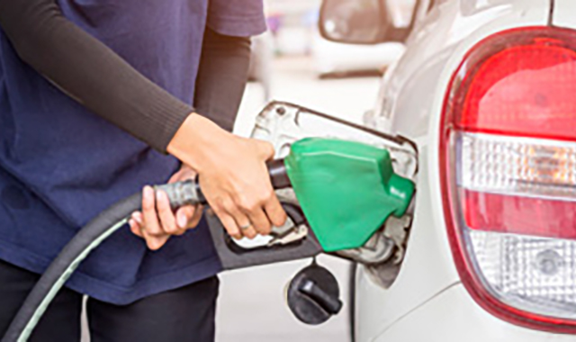 Pessoa abastecendo carro em posto de combustível, com símbolo de economia.