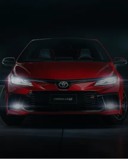 Carro vermelho da Toyota, com faróis acesos brilhantes.