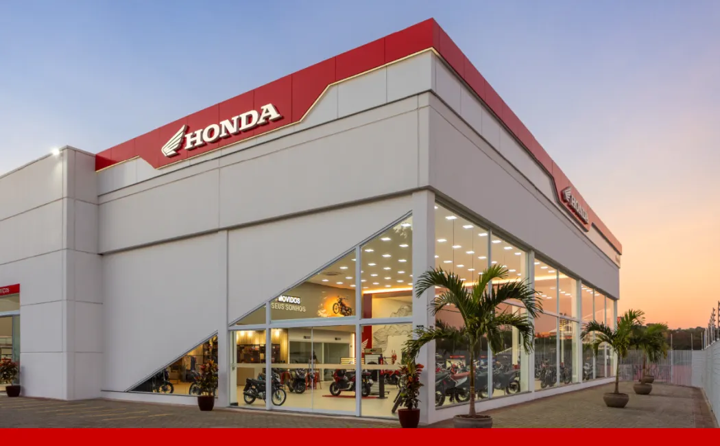 Imagem de uma mulher em cima de uma moto Honda em frente a uma concessionária