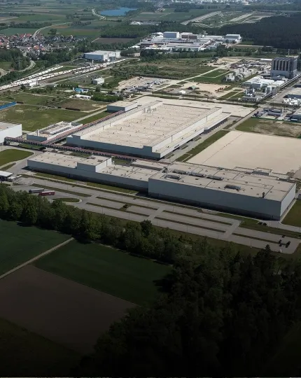 Vista aérea de um complexo industrial da Audi cercado por campos