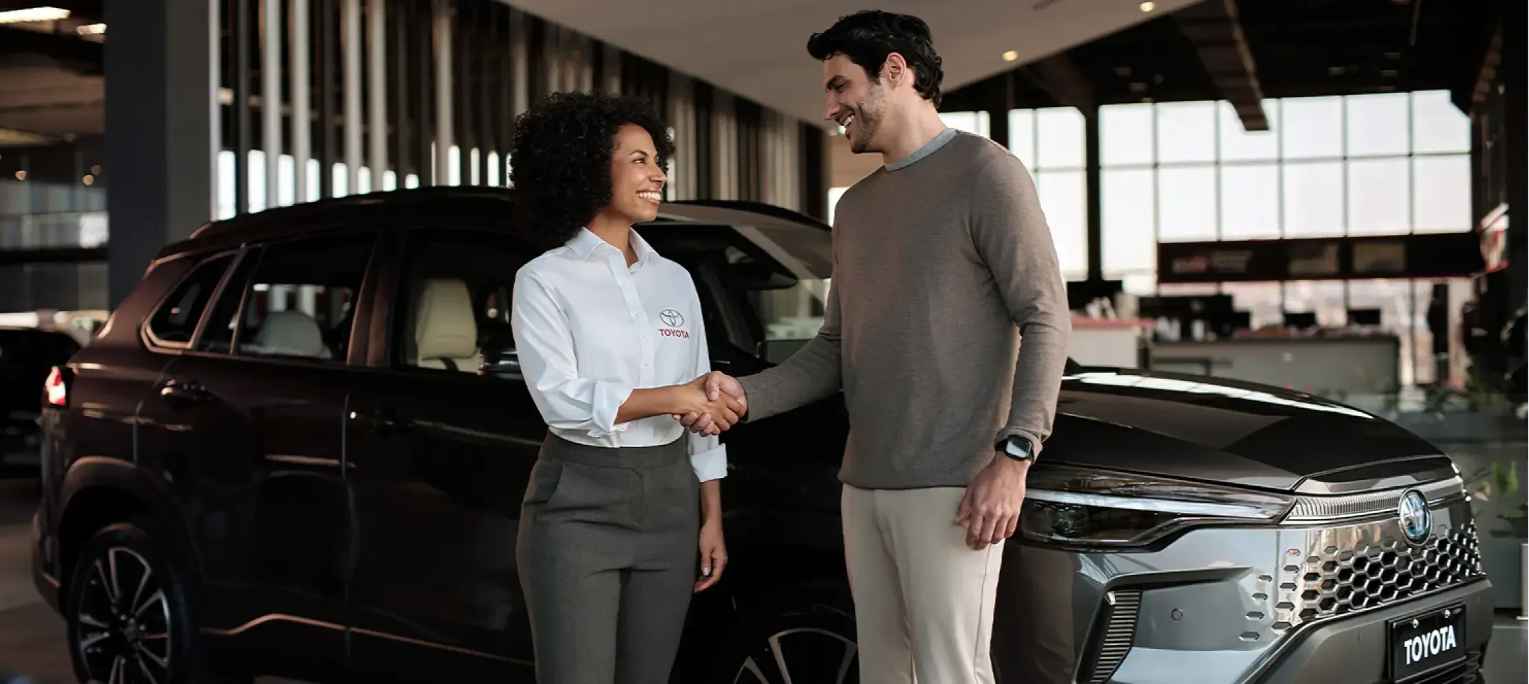 Homem apertando mão de vendedora Toyota em concessionária.