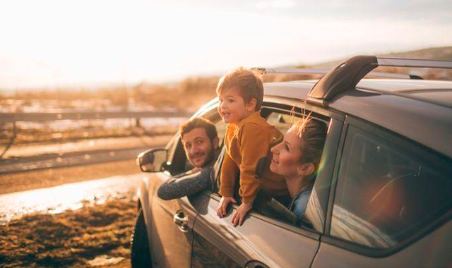 Criança sorrindo no banco de trás do carro durante viagem em família