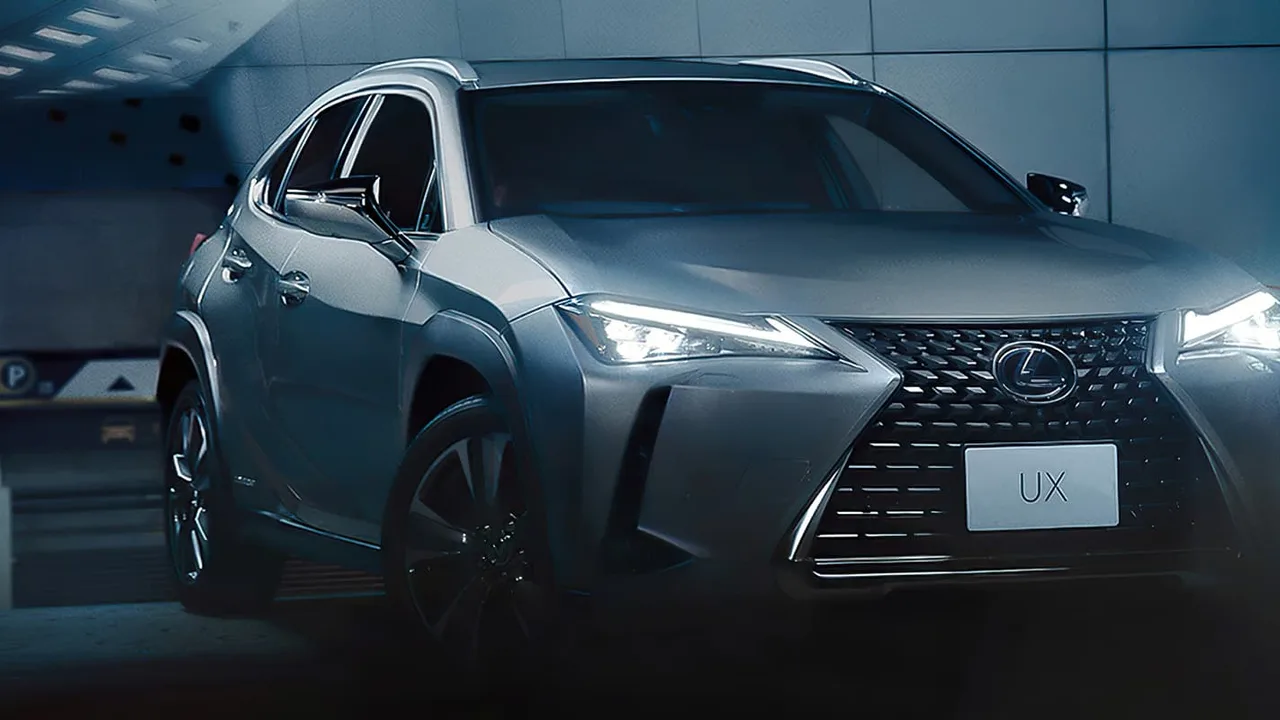 Lexus UX cinza com os faróis acesos, estacionado em um túnel iluminado