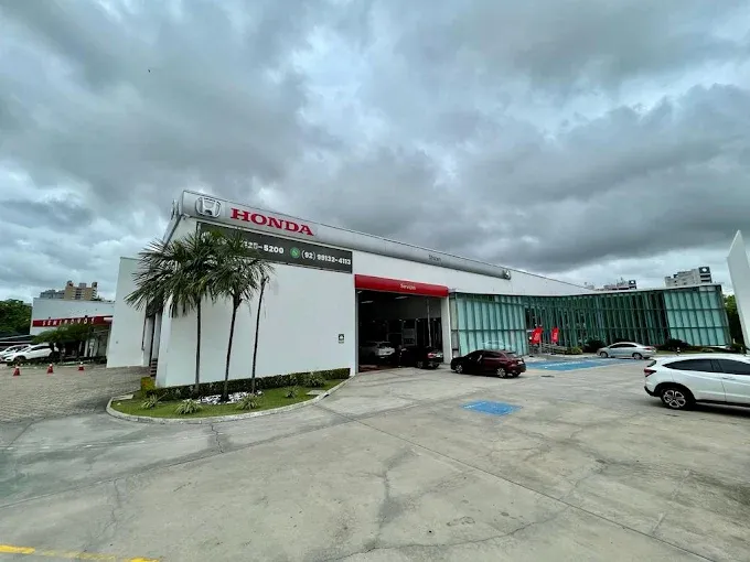 Imagem de uma mulher em cima de uma moto Honda em frente a uma concessionária