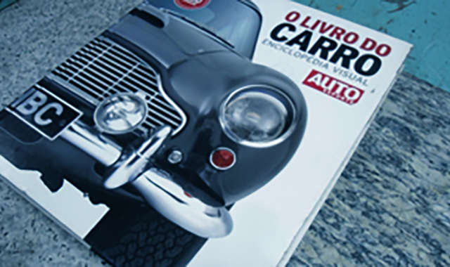 Pilha de livros sobre carros em uma mesa, em casa.