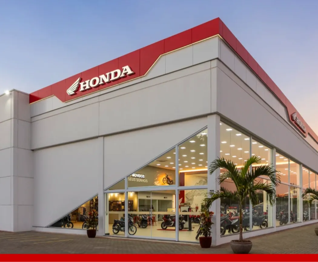 Imagem de uma mulher em cima de uma moto Honda em frente a uma concessionária