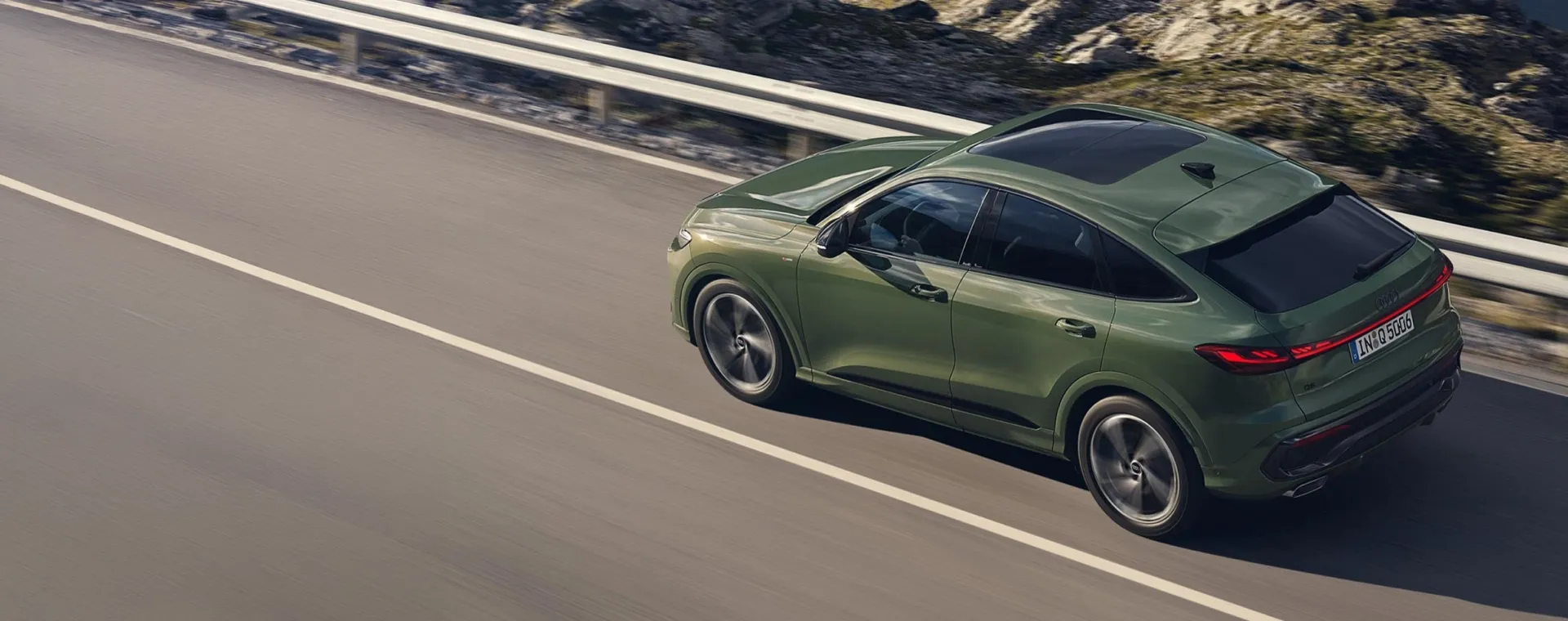 Audi Q5 Sportback verde em movimento em estrada de montanha, visto de cima