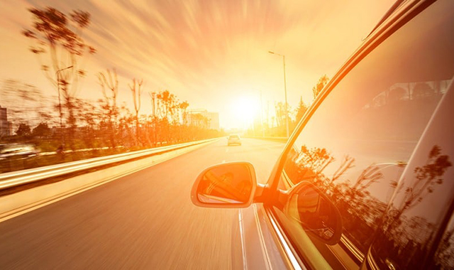 Carro estacionado sob o sol forte, com um protetor solar no para-brisa.