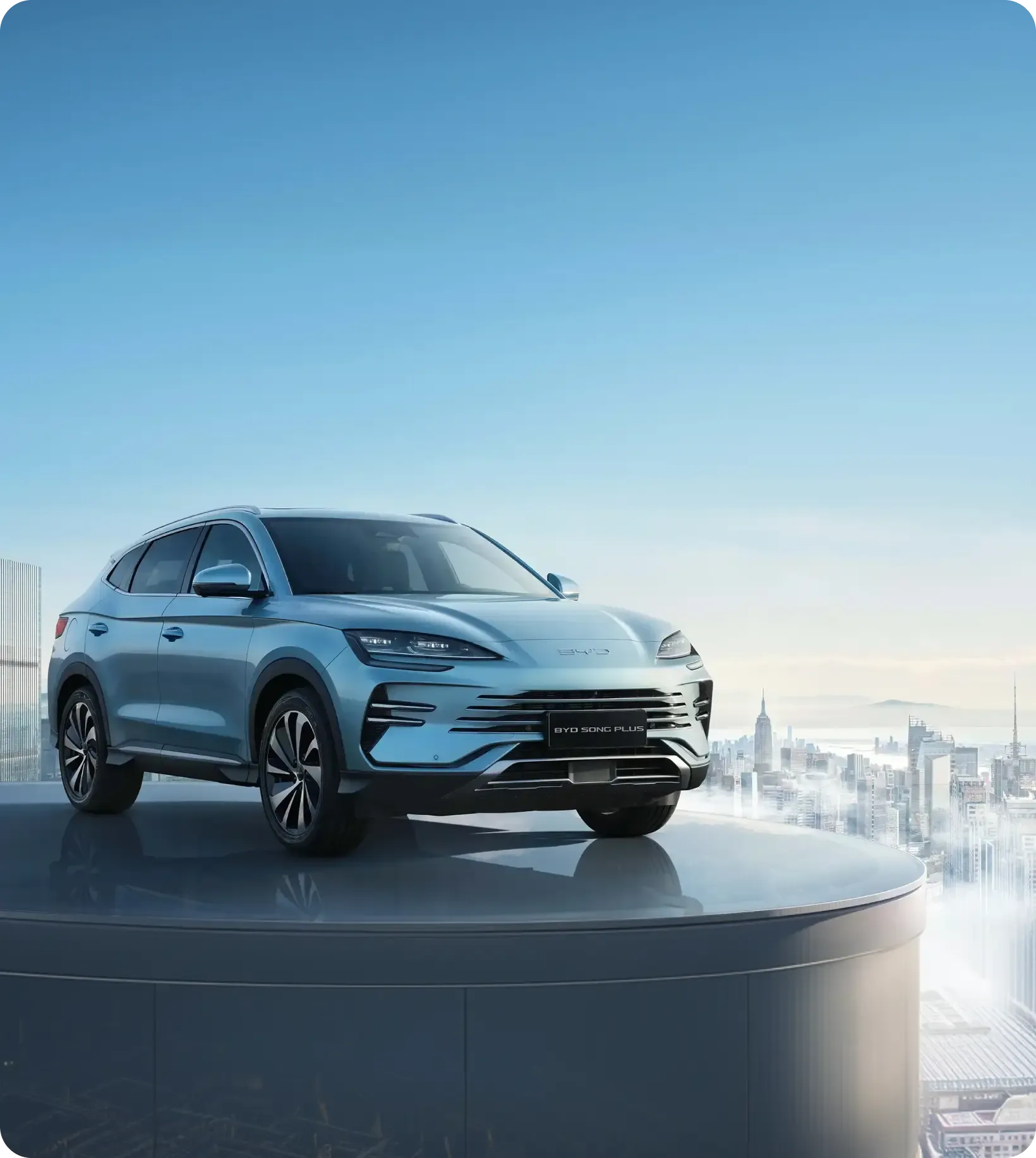 BYD SONG PLUS em uma estrutura alta que permite ver o céu e a cidade atrás.