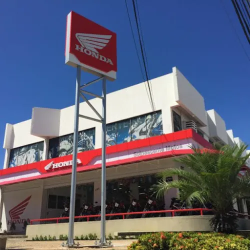 Imagem de uma mulher em cima de uma moto Honda em frente a uma concessionária