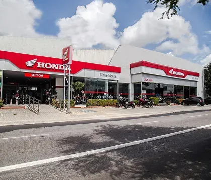 Imagem de uma mulher em cima de uma moto Honda em frente a uma concessionária