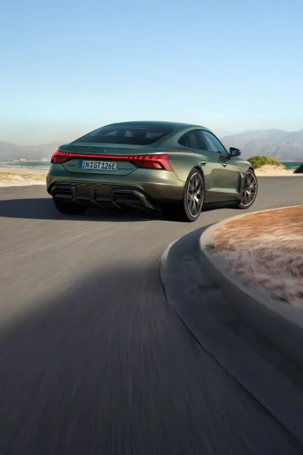 Audi RS e-tron GT verde em movimento em estrada litorânea, visto de trás