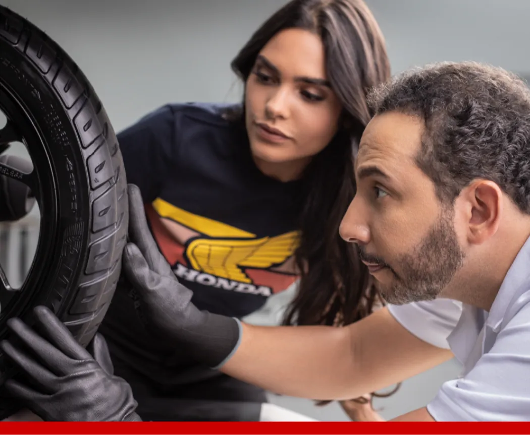 Imagem de uma mulher funcionária da Honda Motos com um cliente enquanto os dois olham para um tablet