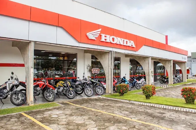 Imagem de uma mulher em cima de uma moto Honda em frente a uma concessionária