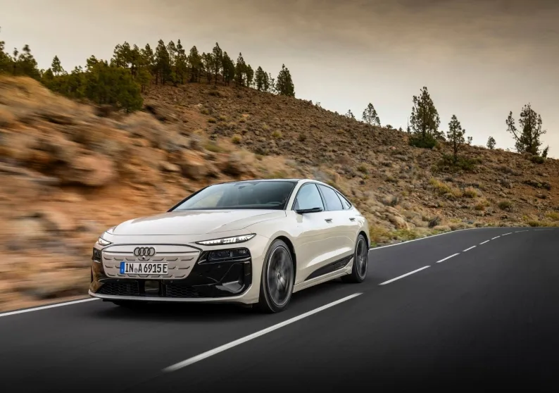 Audi A6 e-tron branco em movimento em uma estrada de montanha