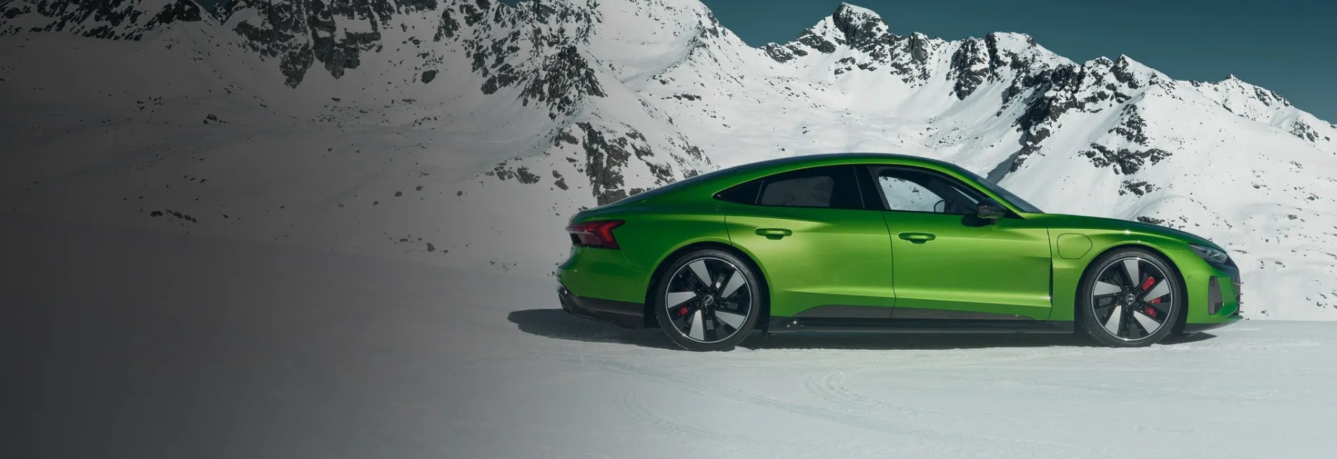 Audi RS e-tron GT verde parado na neve, com montanhas nevadas ao fundo