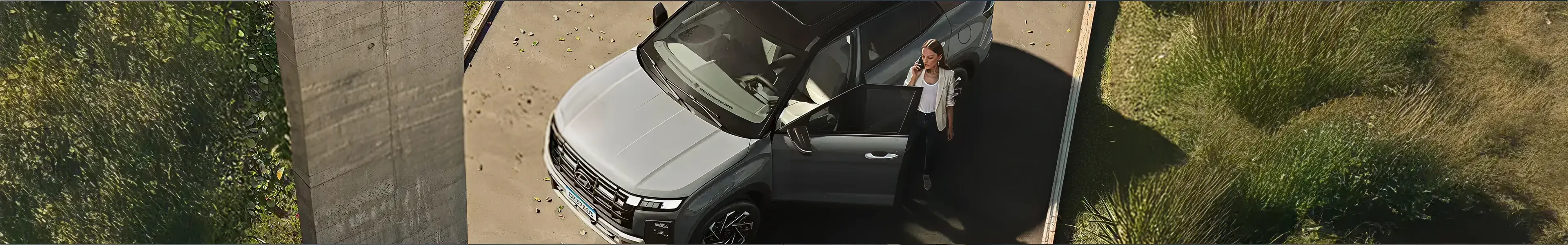 Mulher ao telefone ao lado de carro Hyundai, visto de cima.