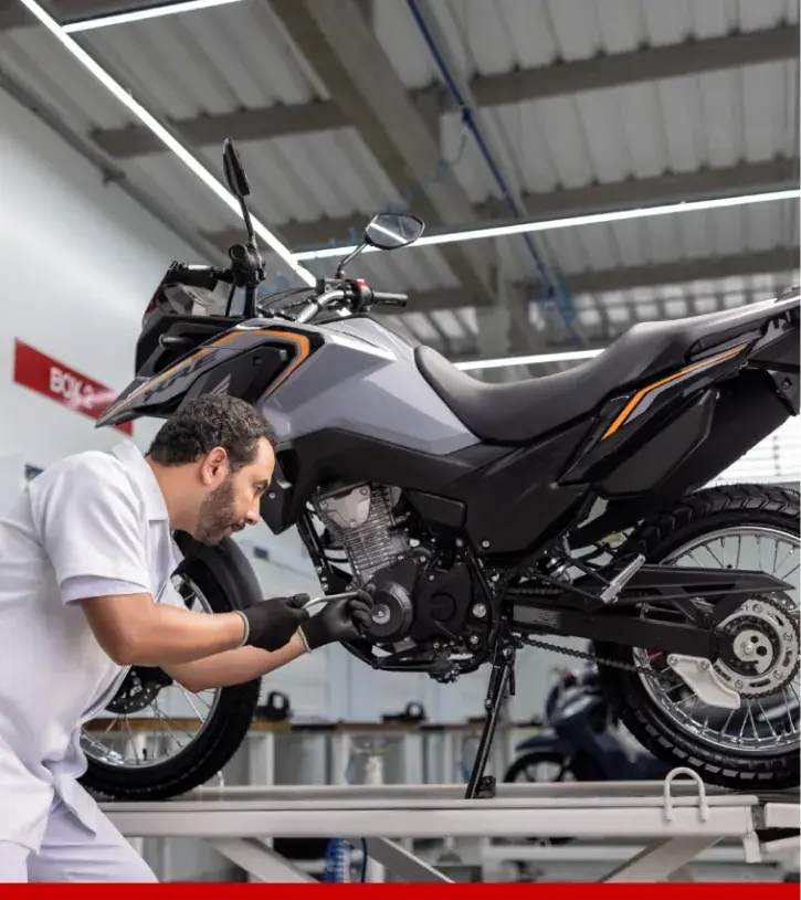 Técnico Honda mostrando o pneu de uma moto a uma cliente