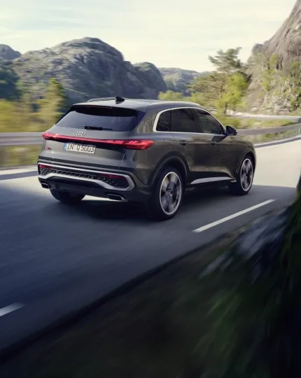 Audi Q5 cinza em movimento em estrada de montanha, visto de trás