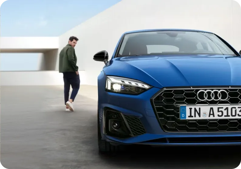 Audi A5 azul visto de frente com um homem caminhando ao lado