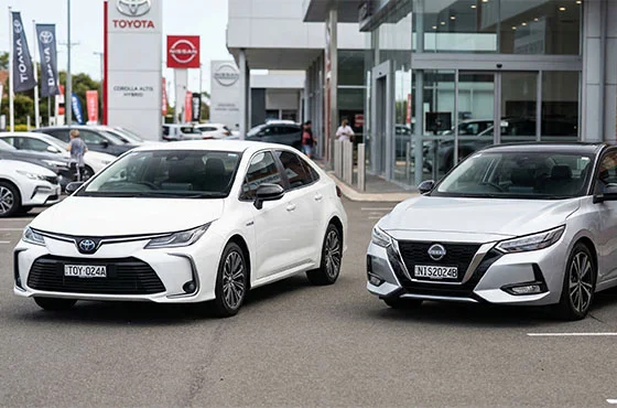 Logos da Toyota e Nissan lado a lado com carros das marcas